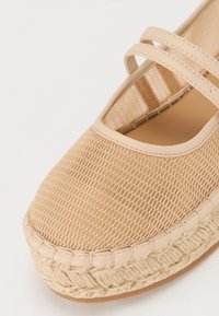 Beige espadrille-sko med nettingoverdel, to tverrstriper og juteinnpakket gummisåle. Rund tå med sømdetaljer.