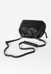 Borsa in pelle nera con una finitura morbida e testurizzata. Presenta un design morbido, una tracolla regolabile e una chiusura con zip superiore.