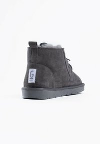 Stivaletti alla caviglia in suede grigio con una morbida fodera in pelliccia, dotati di una linguetta posteriore e di suola in gomma flessibile per comfort e stabilità.