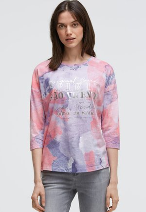 Buntes Langarmhemd mit abstrakten Mustern in Rosa, Violett und Blau. Auf der Vorderseite befindet sich silberner Text, und es hat eine lockere Passform.