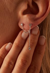Pendientes de cadena de plata con dos piedras de zirconia cúbica, conectados por una delicada cadena, con un acento de gota más larga.