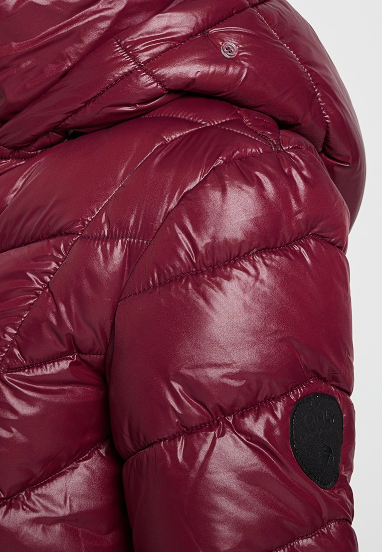 Bordeaux gewatteerde pufferjas met een capuchon en een kleine zwarte cirkelvormige patch op de bovenarm.