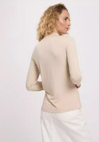Beige long-sleeve top in a fitted design, made from a smooth fabric. Features a high neckline and subtle stitching details.