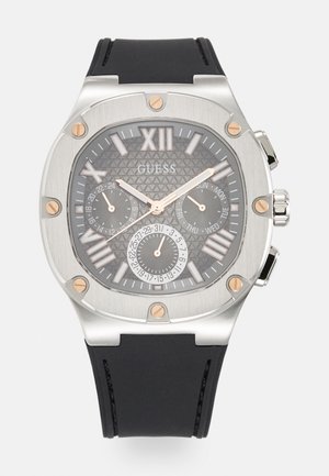 Montre en acier inoxydable argenté avec un cadran noir texturé, des accents en or rose, des index rectangulaires, trois sous-cadrans, et un bracelet en caoutchouc noir.