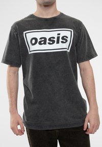 Dark gray cotton T-shirt with a white rectangular graphic reading "Oasis" in bold black letters, featuring a relaxed fit and short sleeves.