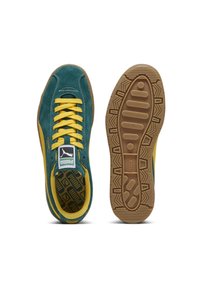 Puma sneakers with a teal suede upper, yellow laces, and logo. Rubber sole features patterned tread for grip. Classic low-profile design.
