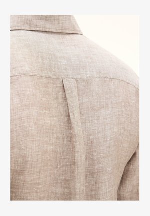 Vista posteriore di una camicia di lino beige che mostra l'imperdibile e il dettaglio della piega centrale a scatola sulla parte superiore della schiena.