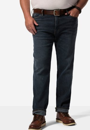Mørkeblå denim jeans med lige ben, opsmøg ved kanten og synlige syninger. Bæret med brune læderstøvler og et mørkt bælte.