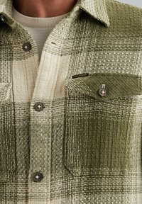 Groene en crème geruite flanellen shirt met een gestructureerde afwerking, voorzien van metalen knopen en een borstzak met merklabel.