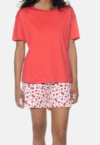 Rotes Baumwoll-T-Shirt mit kurzen Ärmeln, kombiniert mit pinken Shorts mit einem Kirschmuster und schwarzen Konturen, weicher Textur, lässige Passform.