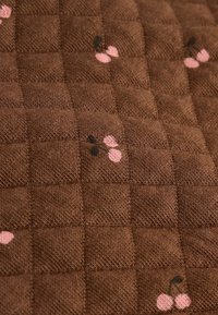 Brązowa tkanina o fakturze z pikowanym wzorem, z małymi różowymi i czarnymi motywami wiśni rozmieszczonymi na całej powierzchni.