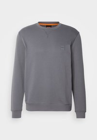 Szary sweatshirt z okrągłym dekoltem, ściągaczami przy rękawach i na dole. Posiada subtelną metkę z logo po lewej stronie oraz pomarańczowe wykończenie przy dekolcie.