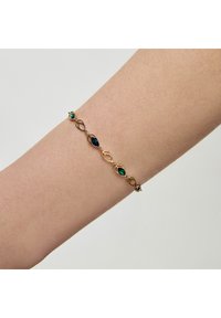 Złota bransoletka z naprzemiennymi, ciemnoniebieskimi i zielonymi kamieniami szlachetnymi w owalnym wzorze, zaprojektowana z myślą o delikatnym dopasowaniu na nadgarstku.