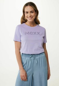 Světle levandulové tričko s krátkým rukávem s nápisem "MEXXX" v dekorativním stylu. V kombinaci se světle modrými širokými džínovými kalhotami. Měkká látka.