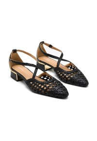 Ballerine nere intrecciate con punta affusolata, aperture aperte e doppie cinghie incrociate. Presentano un tacco basso quadrato con un accento dorato.