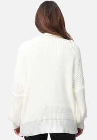 Weißer, oversized Strickpullover mit strukturiertem Muster, weiten Ärmeln und geripptem Saum. Das Design umfasst einen leichten Stoff.