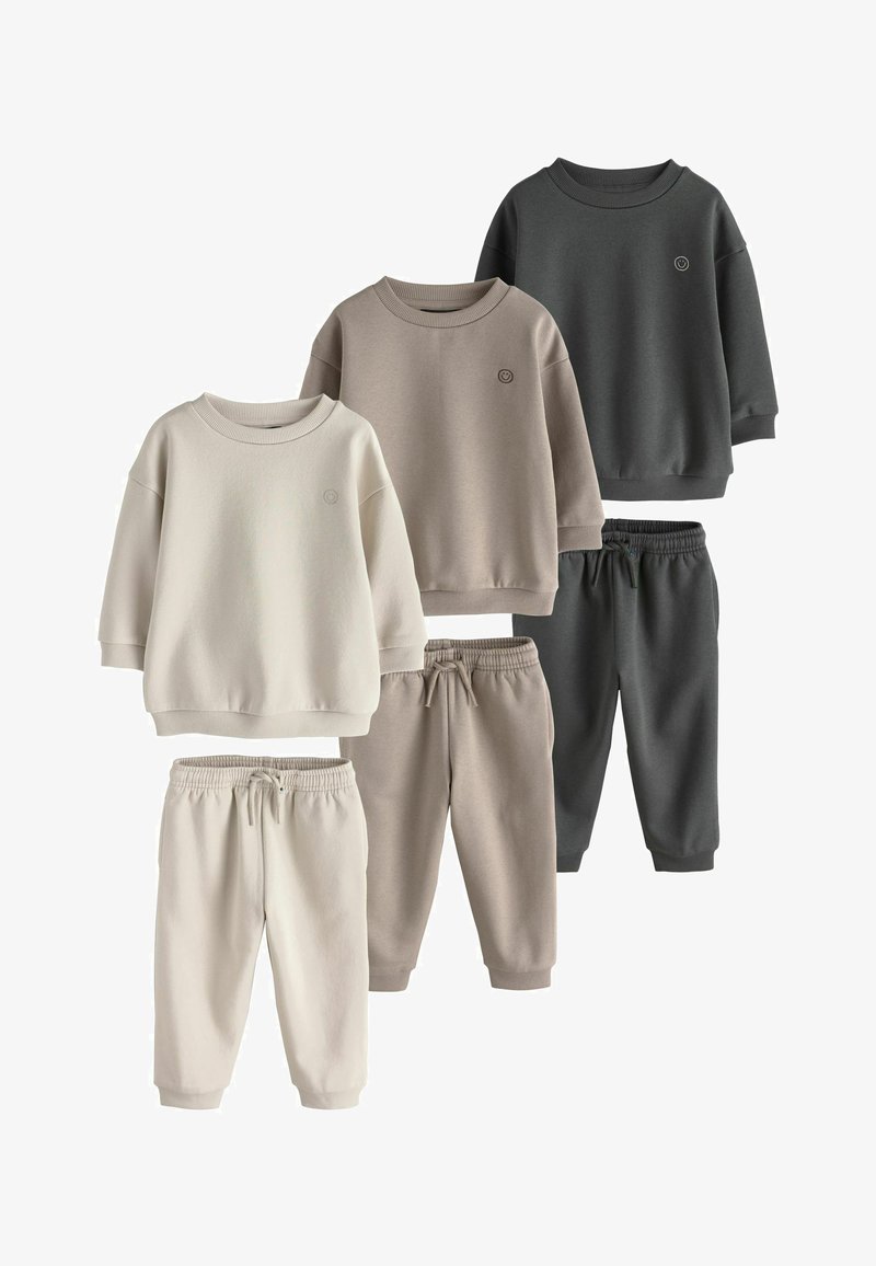 Three sets of long-sleeve sweatshirts and sweatpants in cream, beige, and dark gray with small smiley face logos on the left chest.