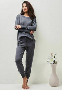 Grau, langärmeliges Oberteil mit entspannter Passform und geripptem Kragen, kombiniert mit passenden, schmal zulaufenden Hosen. Weicher Stoff, mit einem Kordelzugbund.