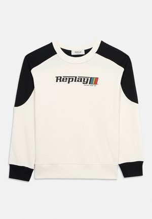 Fehér pulóver fekete vállrésszel és mandzsettával, rajta "Replay Racing Team 1981" felirat és három színes csík a mellkason.