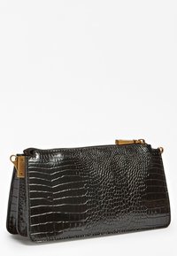 Musta krokotiilinkuviollinen käsilaukku, jossa sileä kiiltävä pinta, vetoketjusuljenta ja kullanväriset korostukset sivuilla. Suorakulmainen muoto, keskikokoinen.
