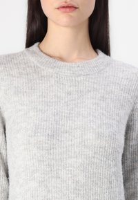 Maglione grigio lavorato a maglia con una texture a coste, scollo rotondo e tessuto morbido. Design leggero e senza cuciture, ideale per sovrapporre.