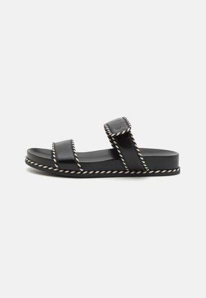 Schwarze Leder-Sandalen mit zwei breiten Riemen, weißem Kordelstich entlang der Ränder und flacher Sohle. Einfaches, minimalistisches Design.
