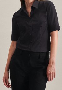 Short-sleeve black shirt made of smooth fabric; features a classic collar, button-down front, and tailored fit, paired with black trousers.
