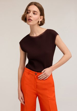 Top corto a righe marroni con maniche corte abbinato a pantaloni arancioni a vita alta. Il top presenta un collo rotondo e una vestibilità comoda, con pantaloni a gamba larga.