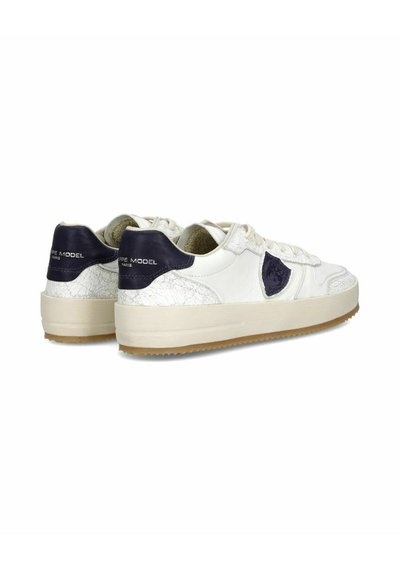 Baskets en cuir blanc avec des accents bleu marine, panneaux texturés et semelle en gomme épaisse. Présente des œillets et un logo sur le talon.