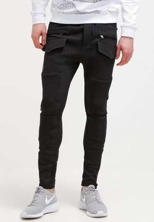Pantalones de chándal negros hechos de una suave mezcla de algodón; cuentan con acentos acanalados, bolsillos laterales y un diseño ajustado.