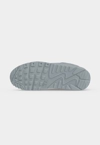 Подметка на светлосив Nike маратонка с текстуриран протектор и лого "NIKE", вдълбано близо до центъра.