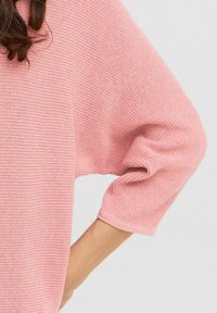 Maglione a coste di un rosa chiaro, caratterizzato da una vestibilità rilassata e maniche a tre quarti. Texture morbida con delicati dettagli a punto.