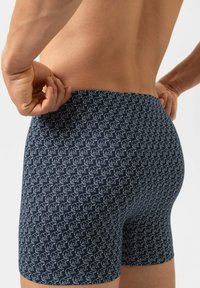 Boxer bleu marine avec un motif d'éléphants blancs, fabriqué en tissu doux et extensible. Il présente une coupe ajustée et une ceinture élastique.