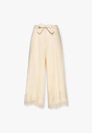 Pantalon crème à jambes larges avec une ceinture en tissu nouée en nœud à la taille et un bord en dentelle le long de l'ourlet.
