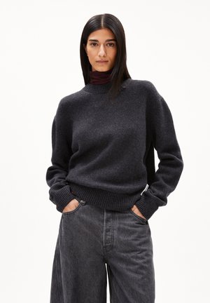 Pull en maille gris foncé avec un col rond et des poignets côtelés, associé à un jean gris foncé à coupe décontractée. Texture lisse, coupe décontractée.