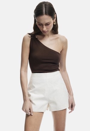 Brauner, einseitiger Top mit dekorativem Knopf; kombiniert mit weißen Shorts mit geprägtem Blumenmuster und glatter Textur.