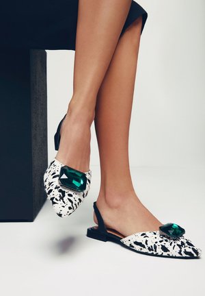 Mocasines tipo slingback con punta afilada, con un patrón salpicado en blanco y negro, un acento de gema verde de gran tamaño y un tacón bajo.