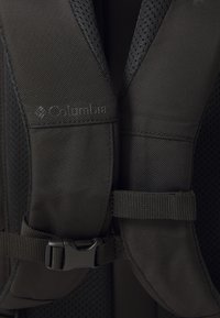 Nahaufnahme von schwarzen gepolsterten Rucksackgurten mit verstellbarem Brustgurt und Columbia-Logo auf einem Gurt.