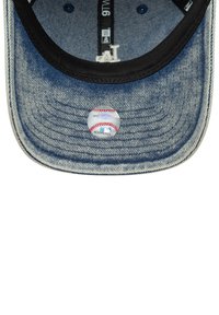 Jeans kapa s crnim vizirima, prikazujući unutarnje detalje i grafiku bejzbol lopte u centru. Šavovi su vidljivi duž oboda.