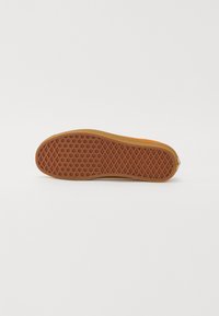 Rubber sneaker sole in orange with a textured grip pattern. Features a zigzag design and rounded heel for enhanced traction and support.