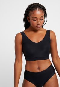 Swartr seamless bralette med V-hals og brede stropper. Kombinert med matchende høyhåndede truser. Myk, glatt stoff uten synlige sømmer.