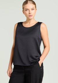 Czarny top bez rękawów z gładkiej tkaniny, z okrągłym dekoltem i luźnym krojem. Posiada subtelne boczne kieszenie i miękko układający się materiał.