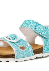 Sandales turquoise étincelantes avec des sangles en feutre doux, boucle réglable, semelle en liège et semelle extérieure en caoutchouc blanc.