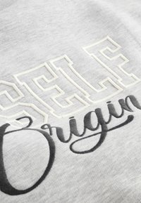 Felpa grigia con lettere ricamate in bianco testurizzato "SELF" e "Origin" in corsivo nero, che mette in risalto il contrasto tra i materiali.