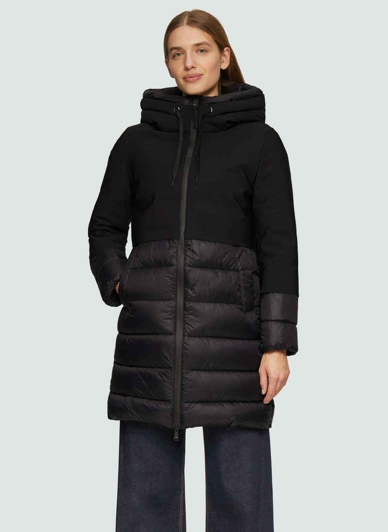 Zwarte capuchonjas met een gewatteerde onderkant. Voorzien van een ritssluiting, twee voorkruiszakken en lange mouwen met contrasterend materiaal bij de manchetten.