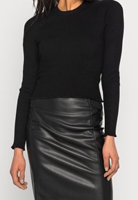 Top long-sleeve noir côtelé avec un col rond et un ourlet effiloché, associé à une jupe crayon en cuir noir élégante.