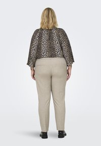 Kapa top z leopardjim vzorcem in 3/4 rokavi, združena s svetlobezhnimi krojenimi hlačami in črnimi čevlji brez pet. Gladke teksture in preprost dizajn.