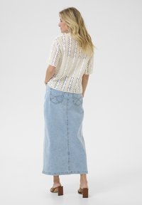 Off-white, knitted, short-sleeve top with openwork pattern; paired with a light blue, long denim skirt featuring back pockets and a straight cut.