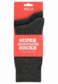 Graue nachhaltige Socken verpackt mit einem leuchtend roten Etikett, das "SUPER nachhaltige SOCKEN" ausweist, mit Text über Fairtrade- und GOTS-Zertifizierung.