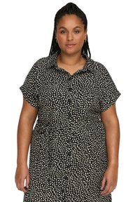 Robe chemise à motifs noir et crème avec des manches courtes, fermeture à boutons sur le devant et taille ajustée. Fabriquée dans un tissu doux et texturé.